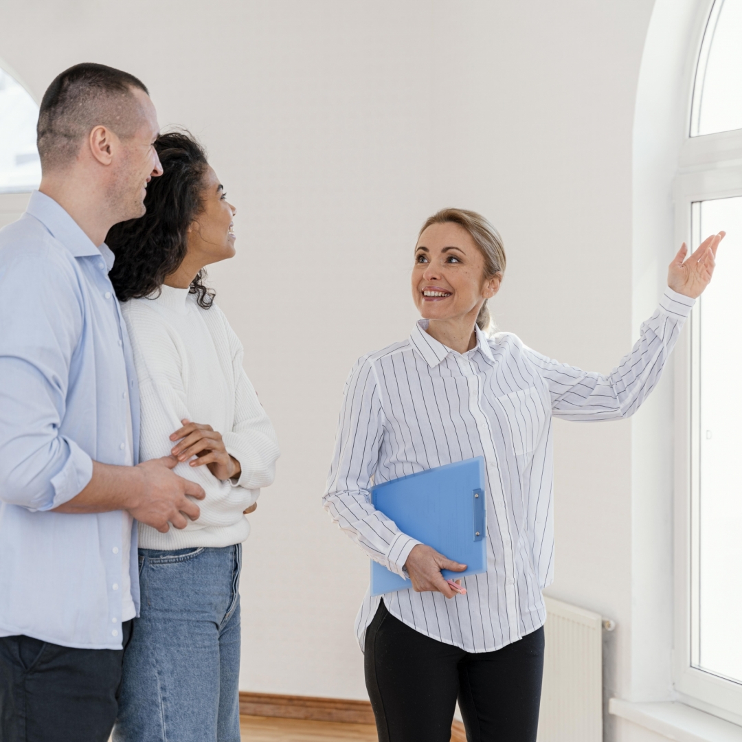smiley-female-realtor-showing-empty-house-young-couple